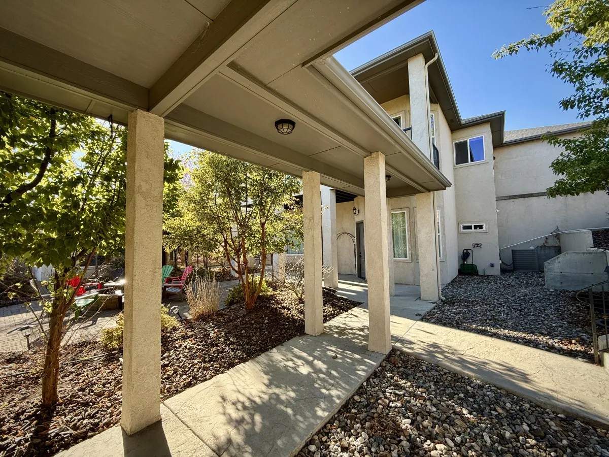 A welcoming view of the casita's exterior features the covered walkway, a landscaped garden rich with greenery, and the inviting front entrance. The environment feels peaceful, accessible, and offers a glimpse into the shared outdoor space ideal for pet walks and relaxation.