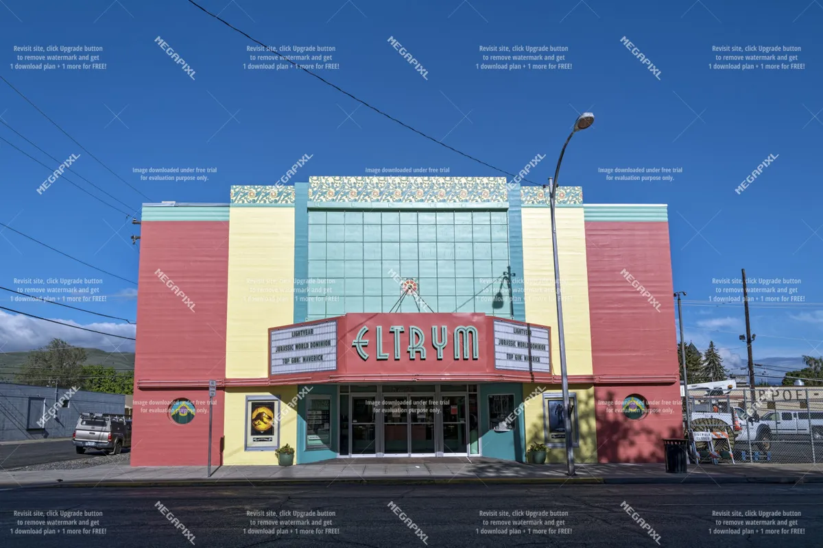 This image captures the vibrant exterior of the ELTRYM theater in downtown Baker City, featuring its colorful art deco facade and prominent marquee. People are seen gathering, hinting at community events, film screenings, or live performances.