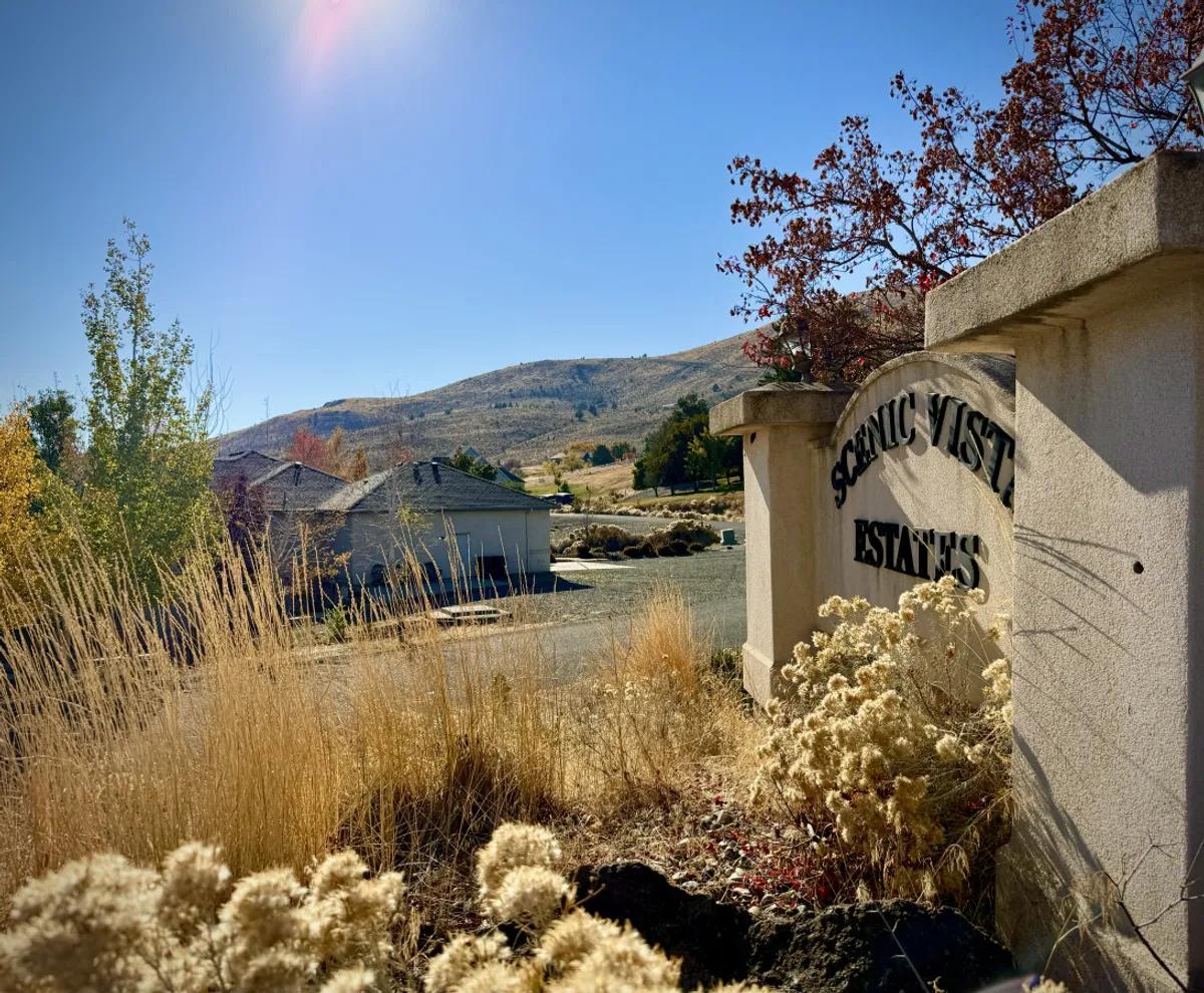 This image showcases the sign for Scenic Vista Estates with rolling hills and natural vegetation in the background. It conveys a sense of arrival and highlights the scenic surroundings that guests can enjoy during their stay.