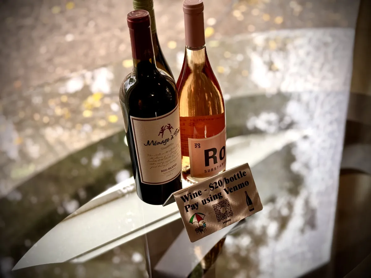 A cozy scene of two wine bottles set on a small counter with a visible payment sign, evoking the experience of sampling local Oregon wines in a relaxed atmosphere.